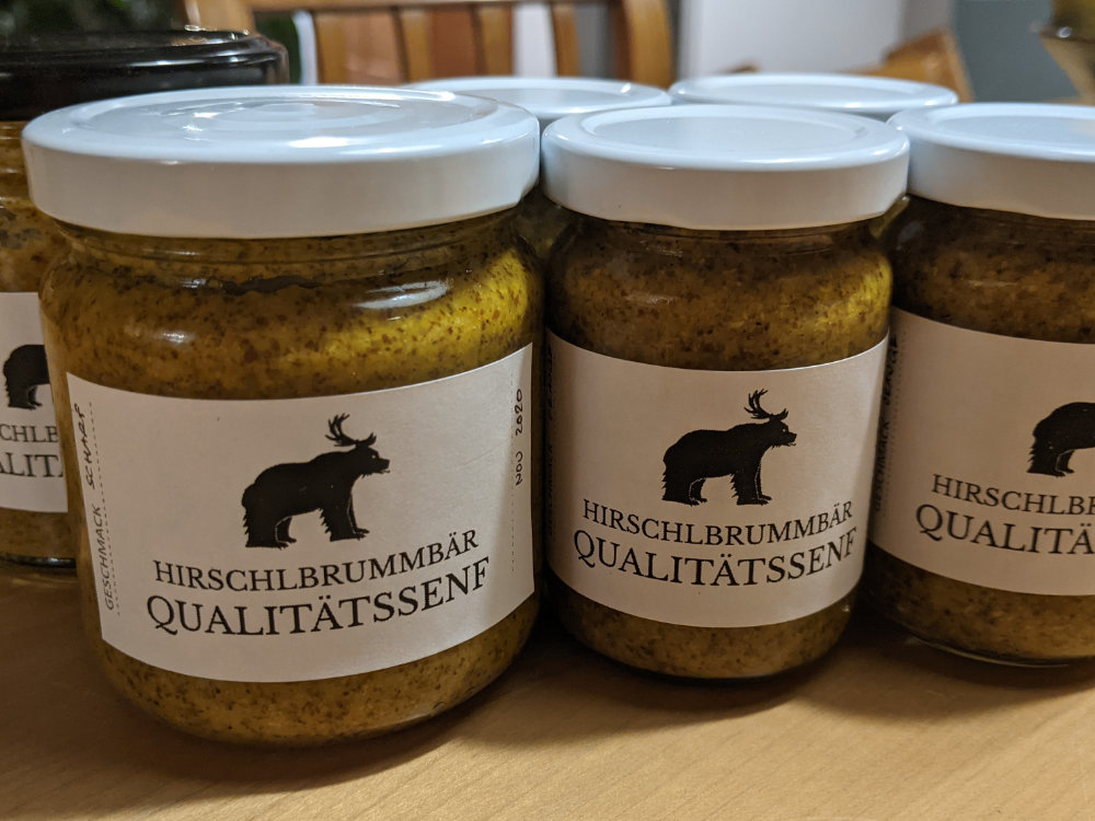 Multiple glasses of mustard, the label states Hirschelbrummbär Qualitätssenf including an image of the Hirschelbrummbär